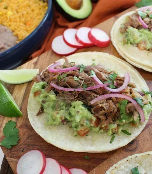 Carnitas street tacos on double corn tortillas with white onion, cilantro, radish and lime