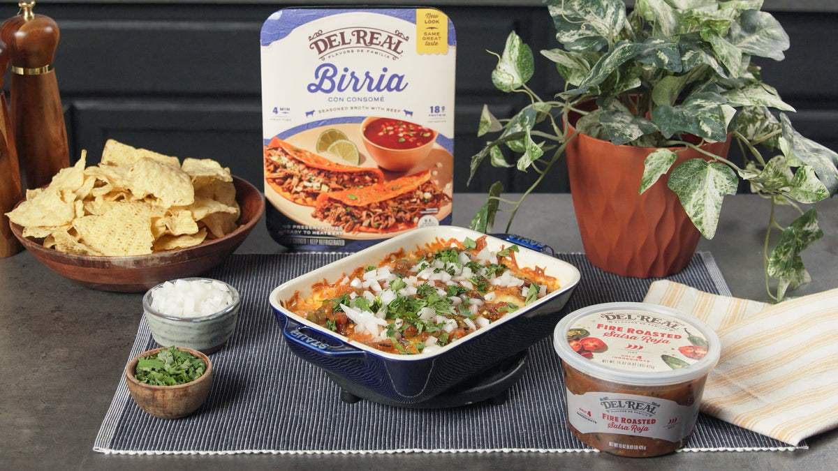 Queso fundido with birria bubbling in a cast iron skillet, with tortilla chips alongside